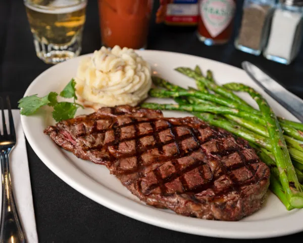 Grilled steak served with roasted asparagus and creamy mashed potatoes on a white plate