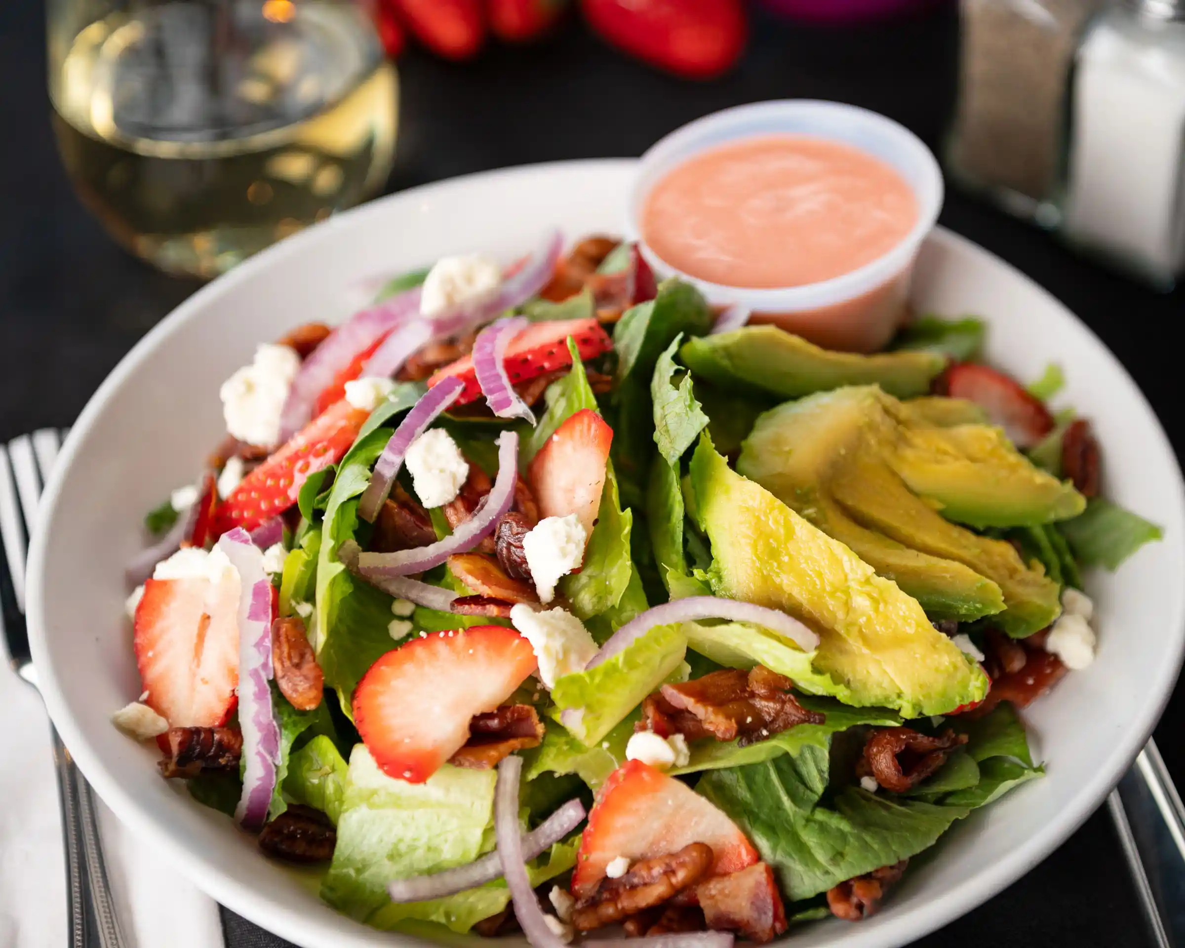 Strawberry, avocado, feta, and pecan salad with pink dressing.